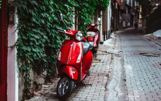 vespa rouge dans une rue pavée